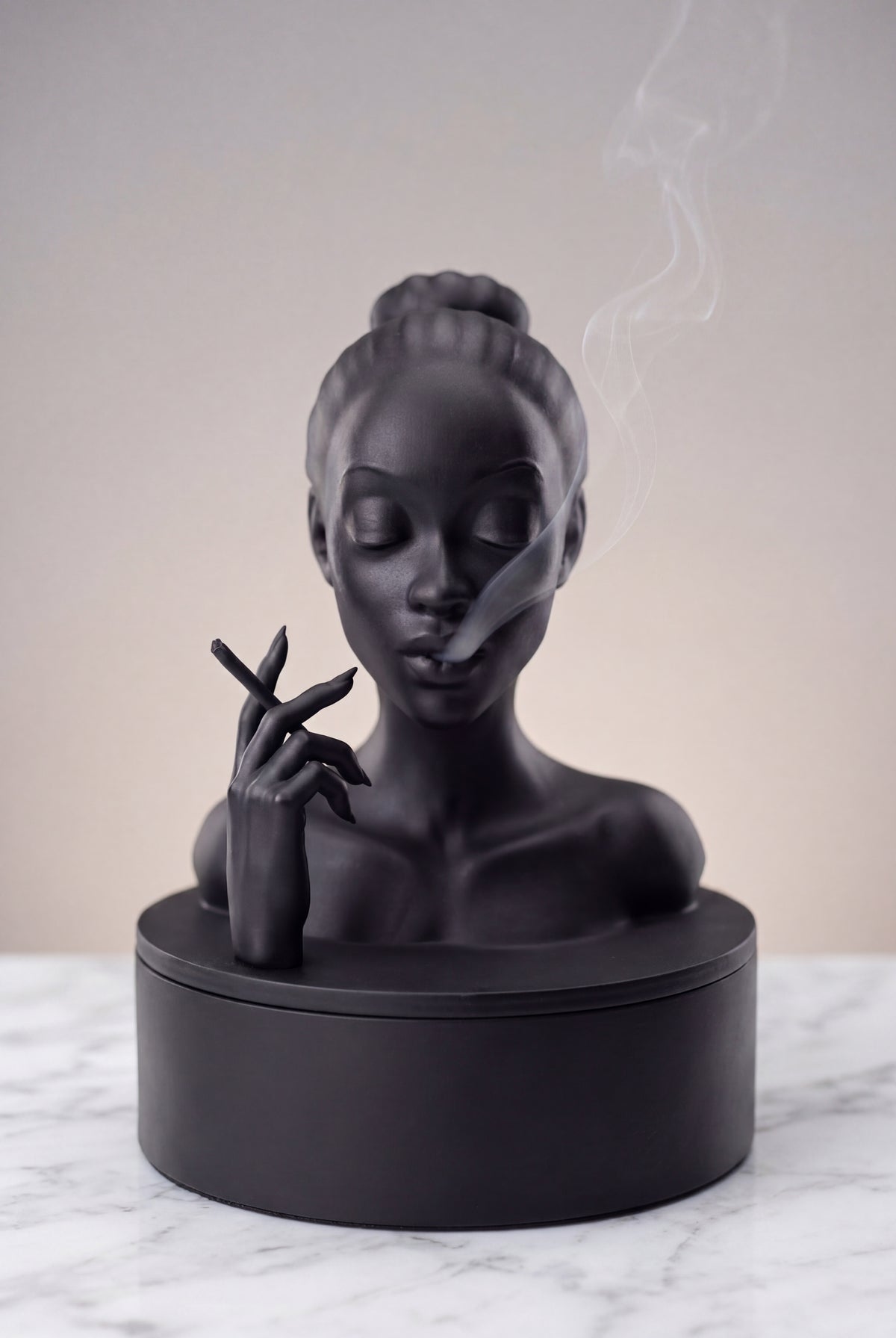 Black sculpture of a woman's bust on a marble surface with a neutral background