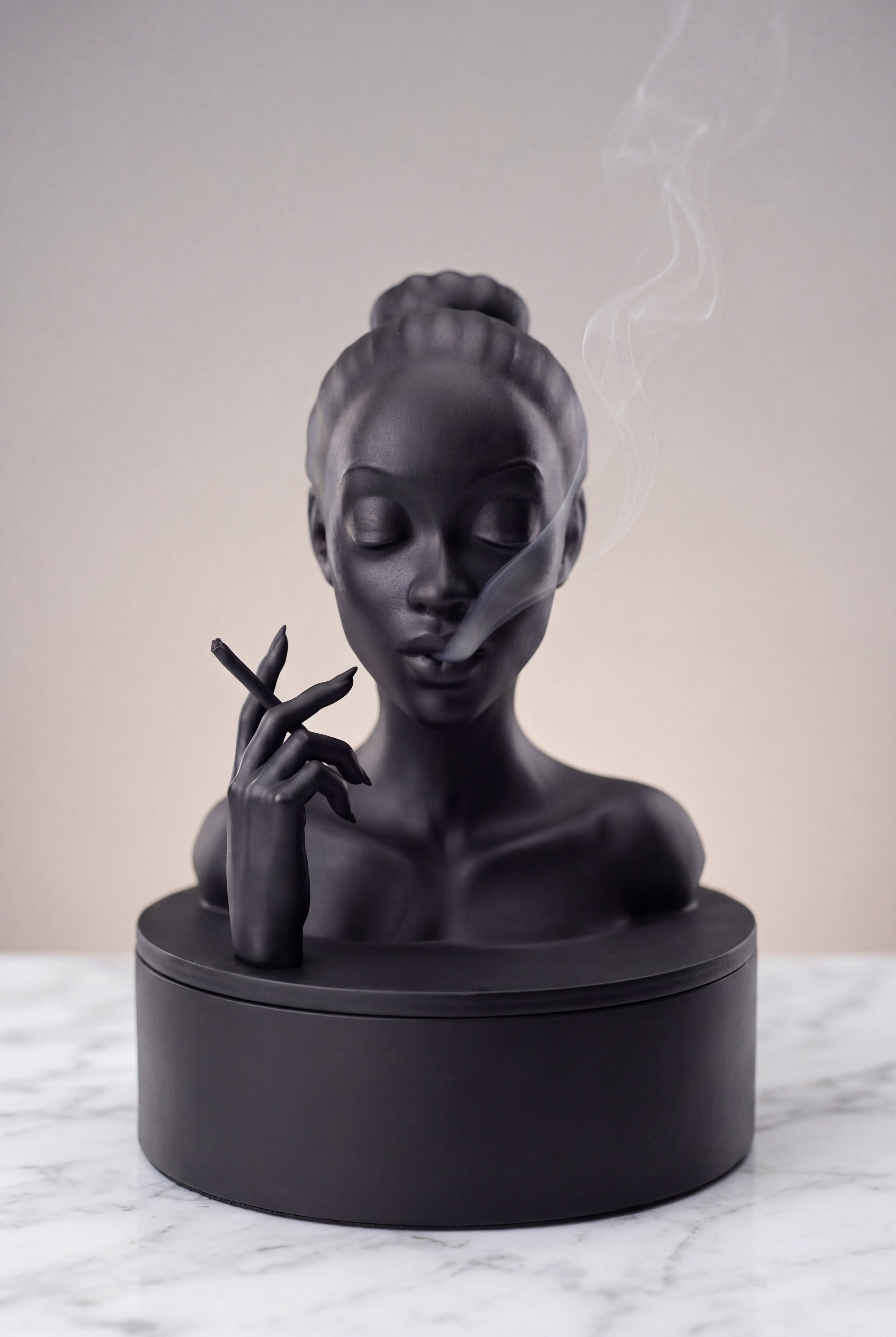 Black sculpture of a woman's bust on a marble surface with a neutral background